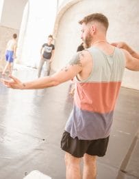 Man with back to camera reaches arm out and gazes down