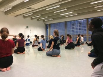 Dancers kneel to face teacher delivering dance sessions