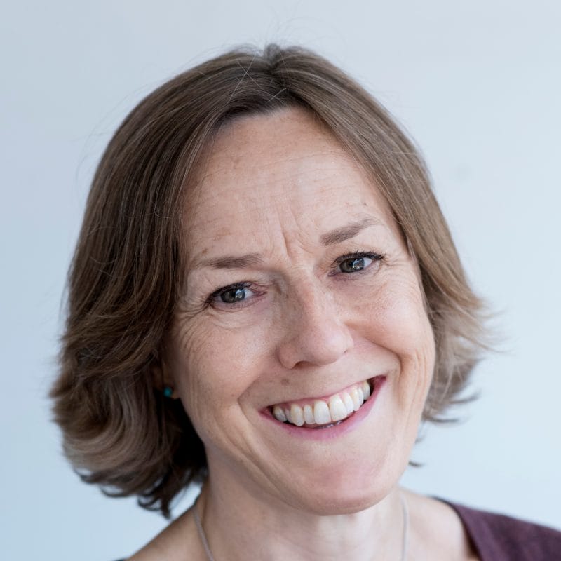 Woman wearing aubergine cardigan smiles at the camera